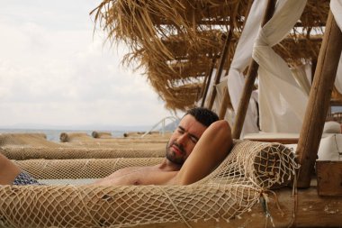 Yakışıklı adam askıya alınmış ağda yatıyor. 