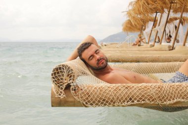 Yakışıklı adam askıya alınmış ağda yatıyor. 