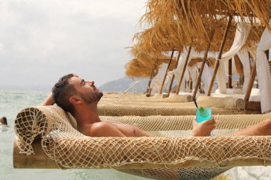 Yakışıklı adam askıdaki ağa uzanmış kokteyl içiyor.