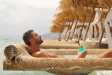 Yakışıklı adam askıdaki ağa uzanmış kokteyl içiyor.