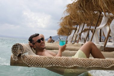 Yakışıklı adam askıdaki ağa uzanmış kokteyl içiyor.