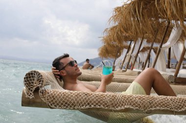 Yakışıklı adam askıdaki ağa uzanmış kokteyl içiyor.