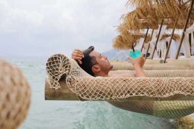 Yakışıklı adam askıdaki ağa uzanmış kokteyl içiyor.