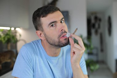 Yakışıklı adam evde sigara içiyor. 