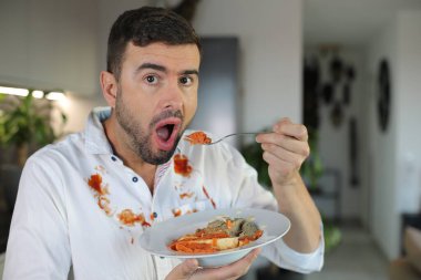 Genç adam mutfakta makarna yiyor.