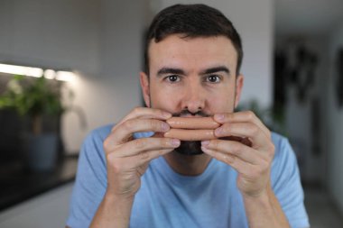 Comedian covering his lips with two sausages clipart