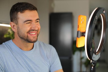 Evde telefonla video kaydeden yakışıklı bir adamın portresi.