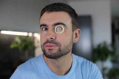 Evde gözlerinde prezervatif olan bir adam var. Yakın plan.