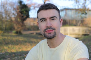 Uzun sakallı yakışıklı bir adamın portresi açık havada takılıyor.