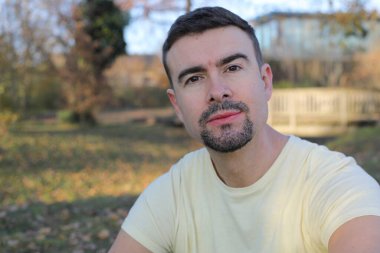 Uzun sakallı yakışıklı bir adamın portresi açık havada takılıyor.