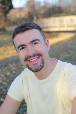 Uzun sakallı yakışıklı bir adamın portresi açık havada takılıyor.