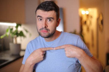 Evde işaret gösteren genç bir adam.