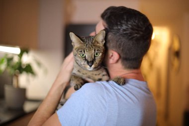 handsome Man holding a Savannah cat clipart