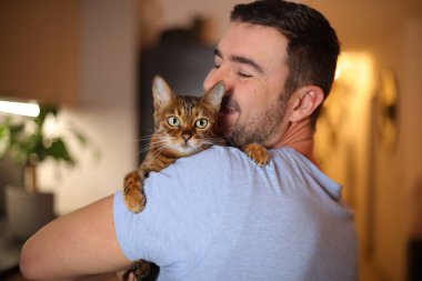 Yakışıklı adam Savannah kedisini tutuyor.