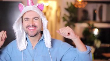 Tek boynuzlu at şapkasıyla dans eden yetişkin bir adam. 