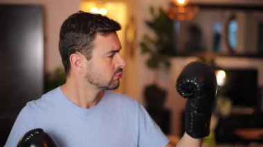 Eldivenli genç adam evde kavga ediyor.