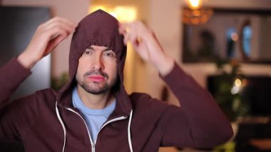 Evde kapüşonlu giyen yakışıklı bir adam.