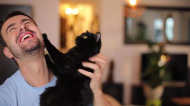 Genç adam elinde bir kedi tutuyor.