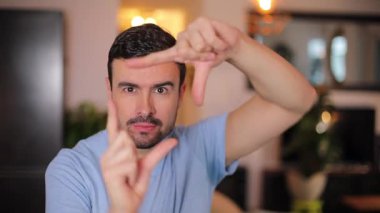 Adam evde parmaklarıyla çerçeve yapıyor.