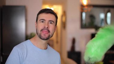 Tüylü toz bezi kullanan yakışıklı adam. 