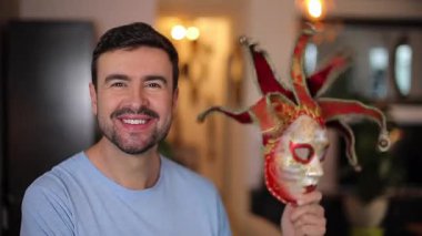 Genç yakışıklı adam karnavalda maske takıyor.