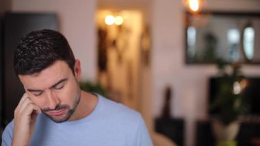 Evdeki oturma odasında düşünen genç bir adamın portresi.