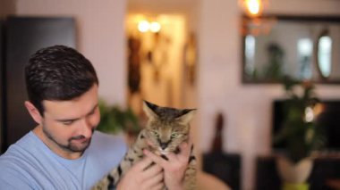 Evde Bengal kedisi olan genç bir adamın portresi.