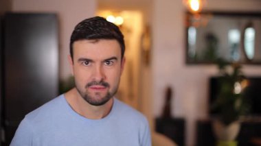 Evdeki oturma odasında şaşırmış bir adamın portresi.