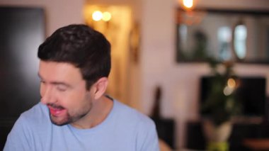 Evdeki oturma odasında duygularını gösteren bir adam.