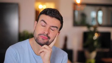 Genç adam evde kamera karşısında komik suratlar yapıyor.