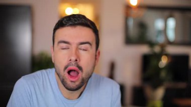 Evdeki oturma odasında şok olmuş gibi bakan adam.