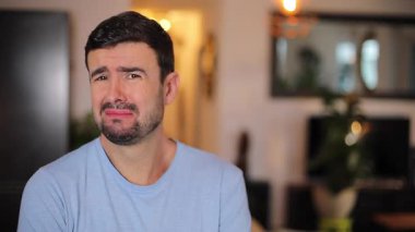 Genç adam evdeki oturma odasında surat yapıyor.