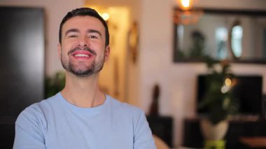 Genç adam oturma odasında, gülümsüyor.