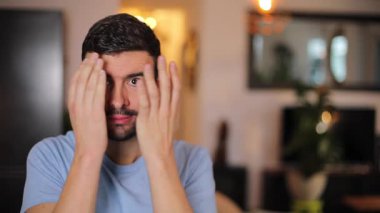 Evdeki oturma odasında sakallı genç bir adamın portresi.