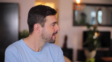 Oturma odasındaki kanepede afiş gösteren genç adamın portresi.