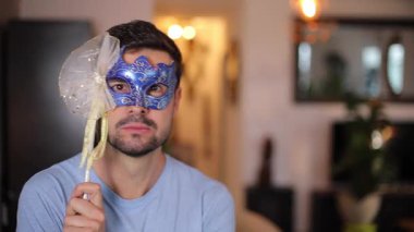 Karnaval maskesi tutan yakışıklı adam.