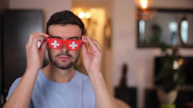 İsviçre renkli güneş gözlüğü takan yakışıklı bir adam.