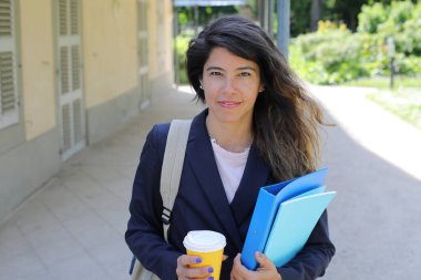 Dosyalar dolusu kahve taşıyan genç bir kadının portresi.