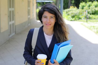 Dosyalar dolusu kahve taşıyan genç bir kadının portresi.