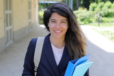 Sırt çantasıyla gülümseyen genç Latin iş kadını