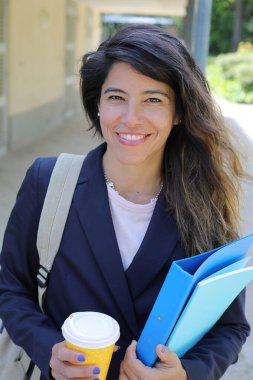 Dosyalar dolusu kahve taşıyan genç bir kadının portresi.