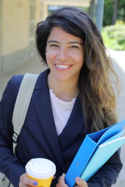 Dosyalar dolusu kahve taşıyan genç bir kadının portresi.