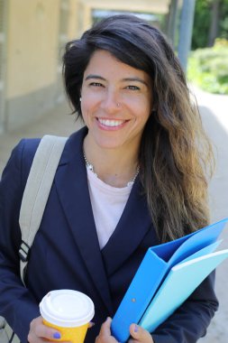 Dosyalar dolusu kahve taşıyan genç bir kadının portresi.