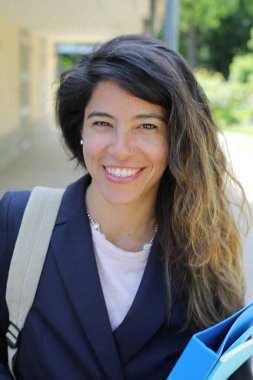 Sırt çantasıyla gülümseyen genç Latin iş kadını