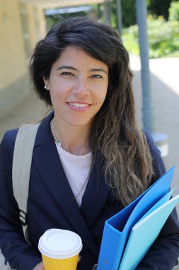 Dosyalar dolusu kahve taşıyan genç bir kadının portresi.