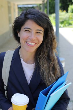 Dosyalar dolusu kahve taşıyan genç bir kadının portresi.