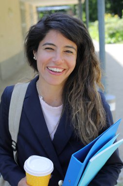 Dosyalar dolusu kahve taşıyan genç bir kadının portresi.