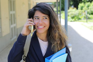 Telefon ve klasörleri olan mutlu genç iş kadını.