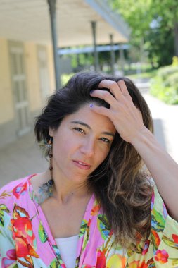 Mutlu genç kadın yaz elbisesi içinde poz veriyor.