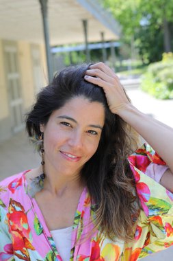 Mutlu genç kadın yaz elbisesi içinde poz veriyor.